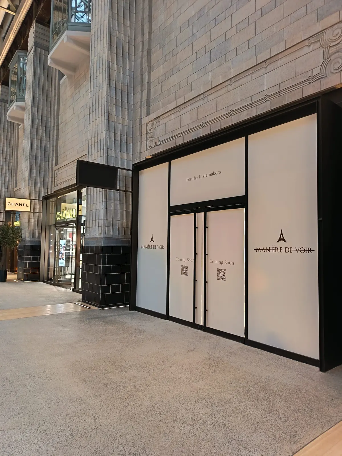 KP Glazing London A shopfront covered with white panels reads “A MANIÈRE DE VOIR” and “Coming Soon.” Nearby are a Chanel shop and a corridor with tall, decorative stone columns.