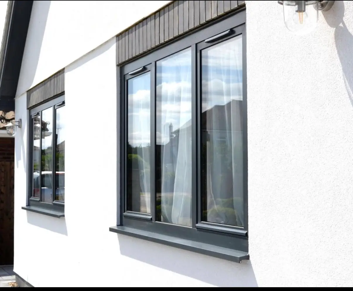 KP Glazing London White exterior wall of a house with two dark-framed, multi-pane windows.