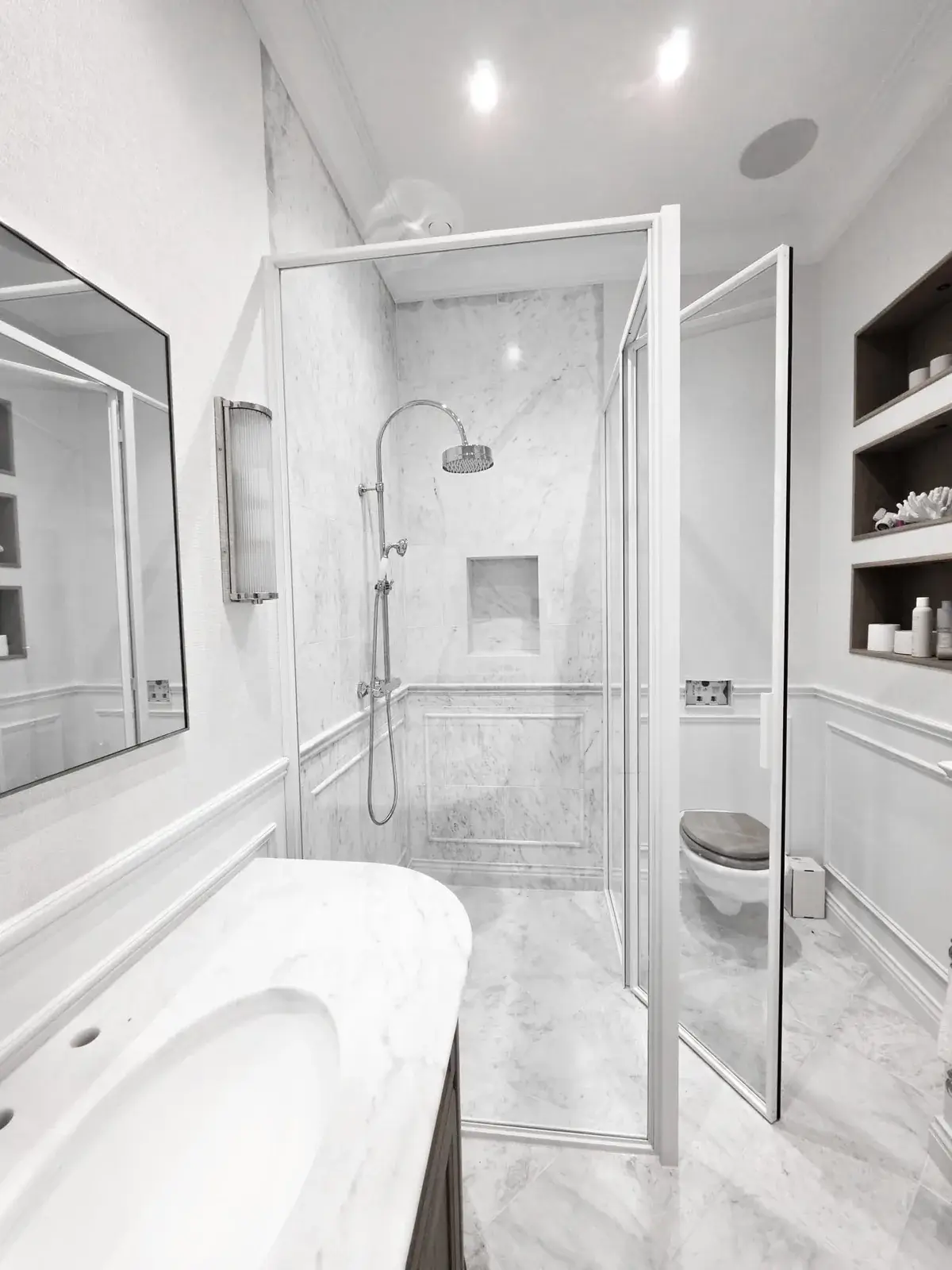 KP Glazing London A modern bathroom featuring a marble shower cubicle, a vanity with a mirror, and a toilet in an enclosed glass compartment.